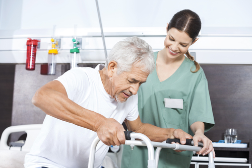 Elderly man going through physical therapy as a nurse helps him.