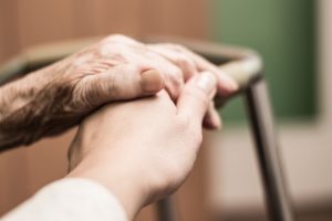 Image of an elderly person's hand touching a younger nurse's hand.