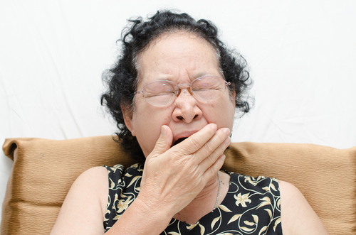 Elderly woman ywning, showing lack of sleeping well.