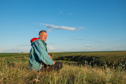 Elderly man sitting outside in the grass.