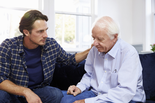 Elderly man experiencing Sundowner’s Syndrome while his son comforts him.