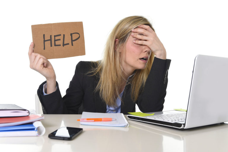 Stressed woman on laptop holding help sign
