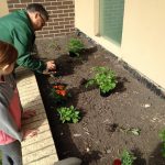 Background. NDSU Barnes County Extension Educator Randy Grueneich helps students plant flowers.