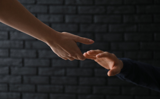 woman-giving-hand-to-depressed-man-against-dark-background-suicide-prevention-concept