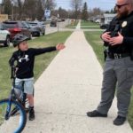 Bike to School Day: Jack Altringer demonstrates a left-hand signal for biking to School Resource Office Sean Hagen. Kids under the age of 10 should ride bike on the sidewalk if one is available but if not, hand signals should be used when biking on the street.