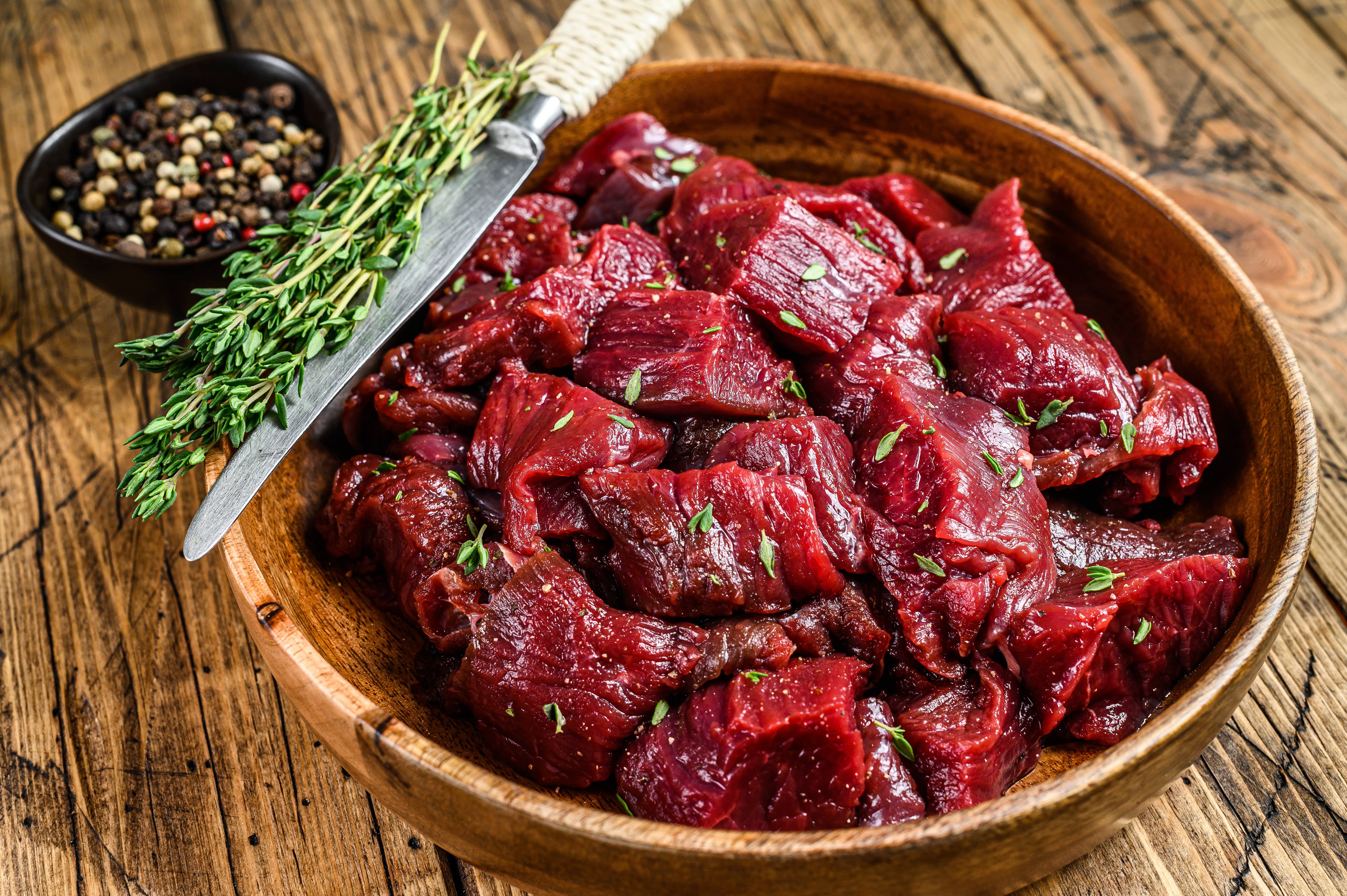 raw-cut-wild-venison-meat-for-a-goulash-in-a-wooden-plate-woode