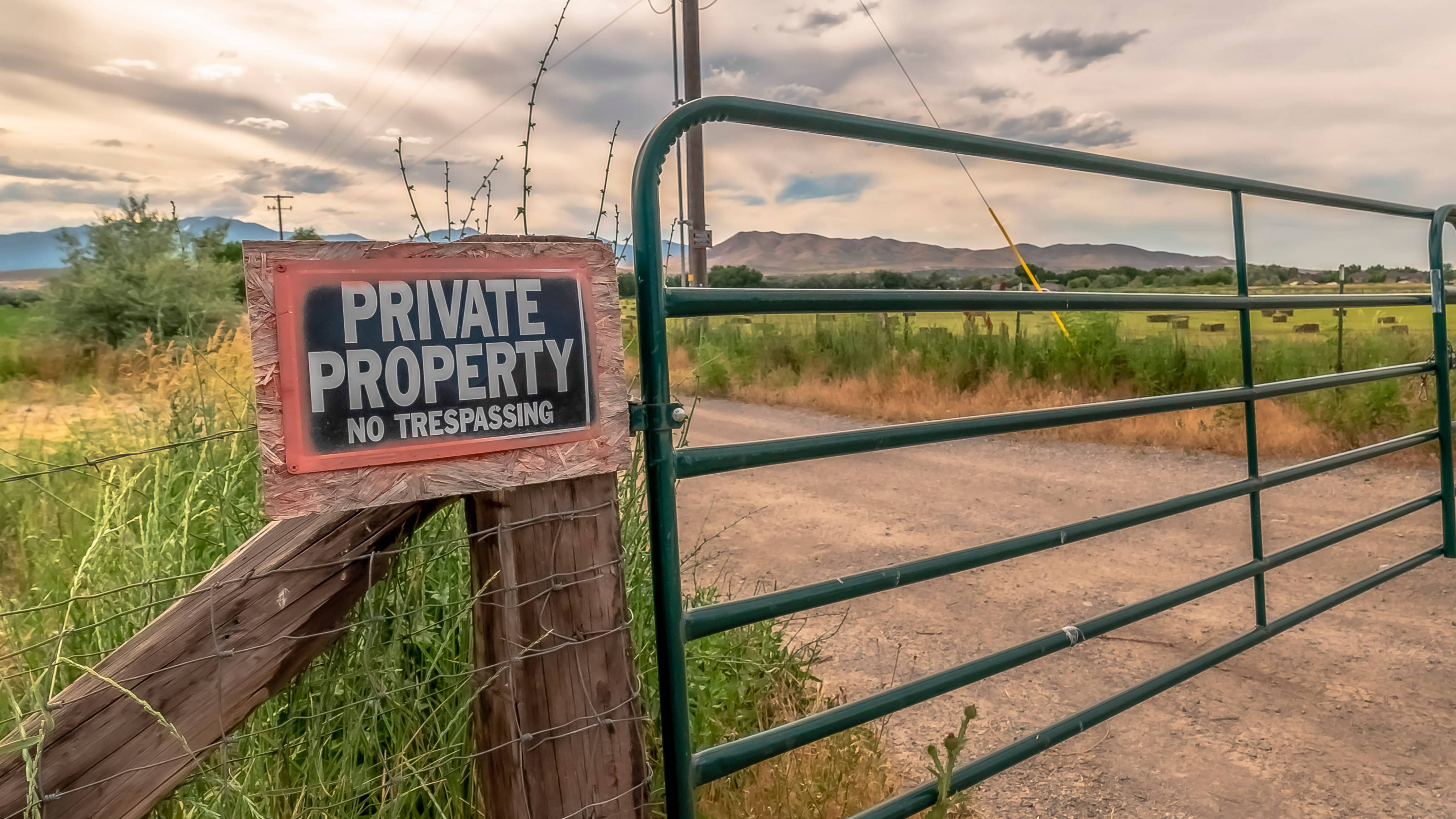 panorama-security-gate-and-fence-with-no-trespassing-sign-against-mountain-and-cloudy-sky