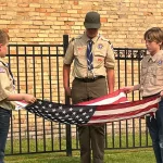 Flag Retirement: Jackson Manlove (left) and August Hochhalter hold the flag while Matthew Holm pays his respects.