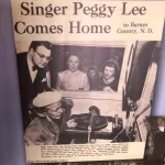 Museum: Bob Ingstad Sr. looks over the shoulder of Peggy Lee in the KOVC studio 1950 as other look into the broadcast studio during her visit to the North Dakota Winter Show.