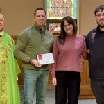 Dietrich Family: L to R; Fr. Paul Duchschere, Luther and Erin Dietrich, and school principal Nick Lee.