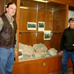 Sea Monster Fossil: Dr. Michael Kjelland (left) and Jay Anderson stand near the fossil pieces of an ancient extinct sea creature found by Jay in Steele County. The pieces are currently on display at Mayville State University.