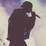 silhouette of rapper performing on stage with foggy background