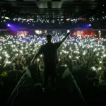 Concert wallpaper. Background with silhouette of rap singer on stage surrounded with fans.