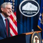 United States Attorney General^ Merrick Garland delivering a speech behind a podium with a mic. Washington D.C.^ USA - Oct 26 2023