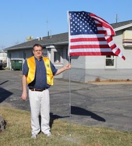 Lions Club President Dave Wright poses with one of the flags that will be put up as part of the new program