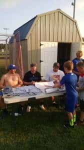 Former Perry Bluejays and current college players Jackson Van Kirk (Luther), Gabe Saemisch (Luther) and Kane Seeley (Iowa State) sign posters and shirts for Perry Youth camp attendees Thursday night.