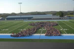 Panorama students pose to assemble a  ribbon in support of Principal Mark Johnston