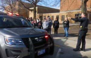 Police Captain Heath Enns (right) explaining equipment on patrol vehicle to students