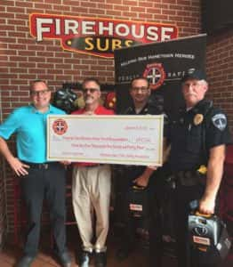 Captain Heath Enns (second from right) and Chief Mark Clouse (right) pose with total grant funding check. Photo courtesy of Enns