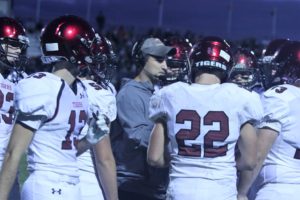 ADM football coach Garrison Carter (gray shirt) speaks with senior Nick Bradshaw (#22) and other members of the Tiger football team during a time out against the Grinnell Tigers on September 7. Photo by ADM Tiger Football/Susan Harshman. 