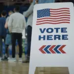 Vote here sign on the floor. Queue of multi ethnic American citizens come to vote in polling station. National Election Day in United States. Political races of US presidential candidates. Civic duty.