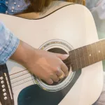 Close up woman's hands playing acoustic guitar.