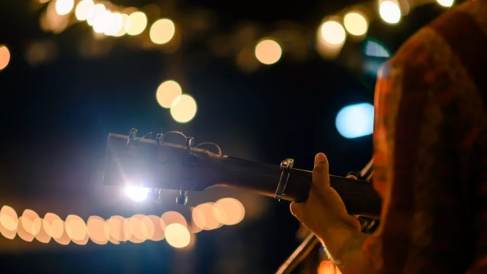 Man play acoustic guitar at outdoor concert with a microphone stand in the front^ musical concept.