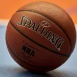 Gdansk^ Poland - 08 02 2024: Close-up of a Spalding NBA basketball resting on a blue and orange court^ focusing on the texture of the ball and the surrounding vibrant colors of the court.