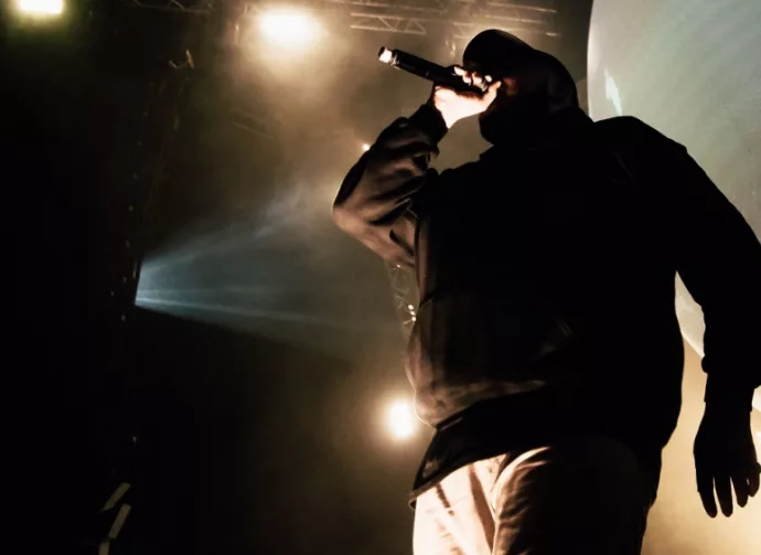 Rapper in hoody with microphone on the stage.