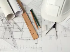 rulers-pencils-compass-hardhat-and-an-eraser-on-architectural-blueprints