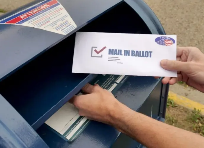 A man puts an absentee mail-in ballot in the mailbox. Circa August^ 2020