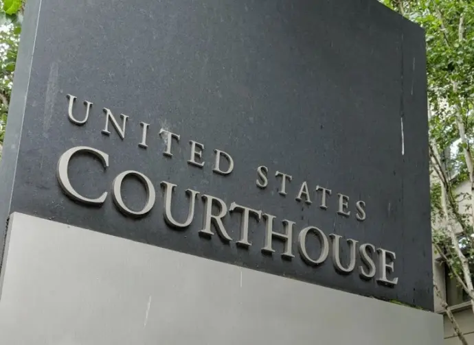The United States Courthouse sign stands tall amidst a serene backdrop of trees at the US District Court in Seattle^ Washington. Seattle - May 17^ 2019: