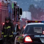 A firefighter stands outside a blaze at a transfer station in East Oakland. Two RVs caught fire in the enclosed lot. Oakland^ California - April 18^ 2026