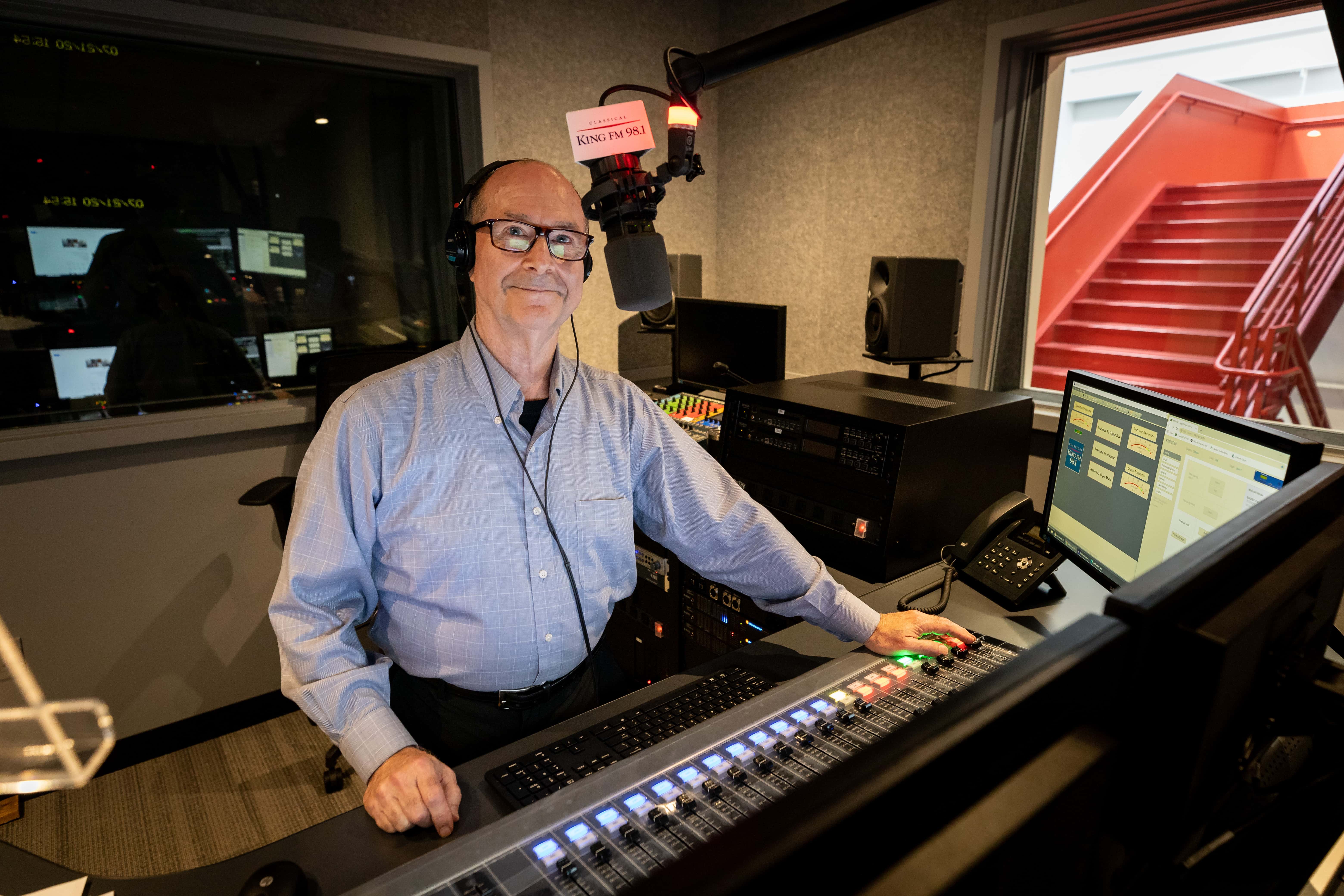 KING FM host Mike Brooks in front of the radio station's master control sound board, July 2020
