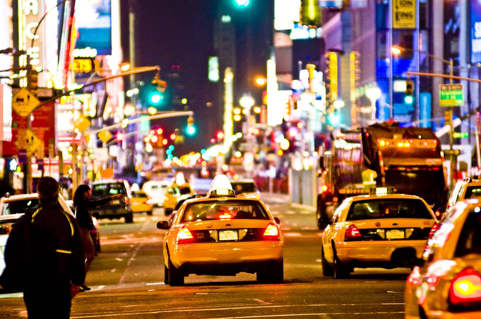 Nighttime photograph of taxicabs on the street in Times Square, New York City