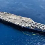 Aerial drone photo of USS Gerald R. Ford latest technology nuclear powered aircraft carrier anchored in deep blue open ocean sea