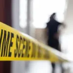 crime scene tape in building with blurred forensic team background
