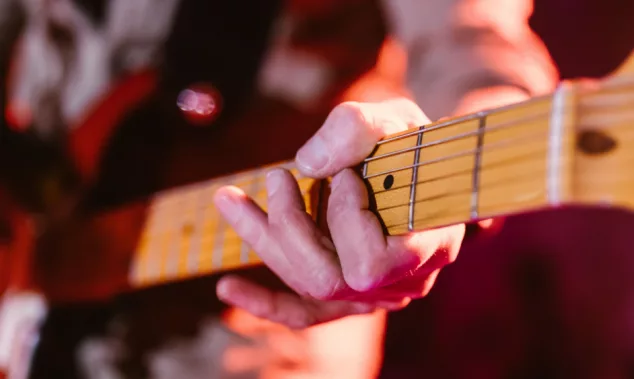 Close up look of hands of a man playing the electric guitar during a concert