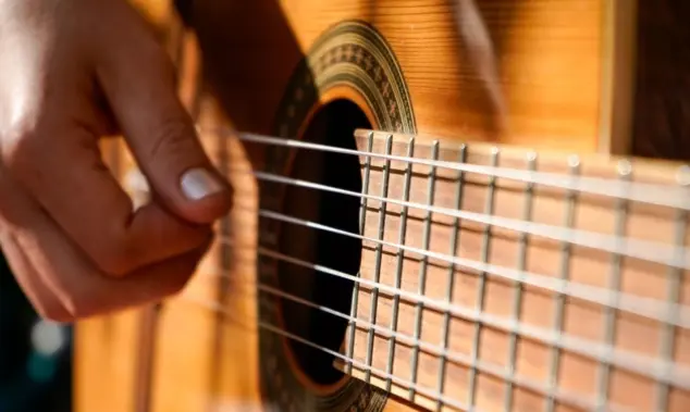 A woman plays an acoustic guitar.
