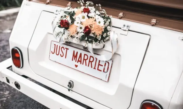 'JUST MARRIED" sign with flower decoration on white wedding car