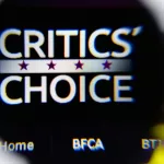 Photo of Critics' Choice Awards homepage on a monitor screen through a magnifying glass.