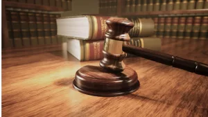 Wooden gavel on the judge's bench with a backdrop of law books