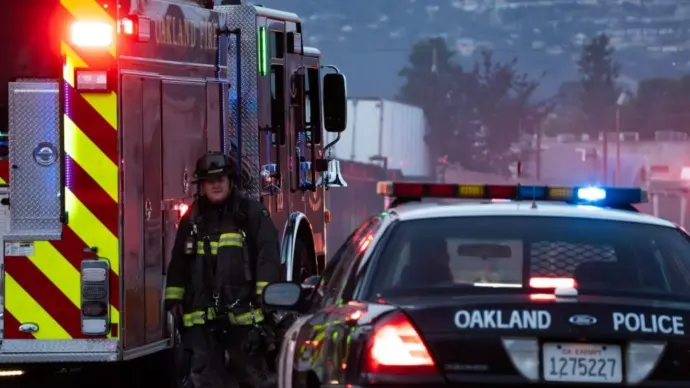 A firefighter stands outside a blaze at a transfer station in East Oakland. Two RVs caught fire in the enclosed lot. Oakland^ California - April 18^ 2026