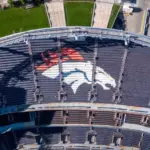 Denver Broncos Logo in Empty Stadium Seats at Empower Field. Aerial Top-Down View of NFL Branding and Architecture in Denver^ Colorado ay 26^ 2022 Denver^ Colorado