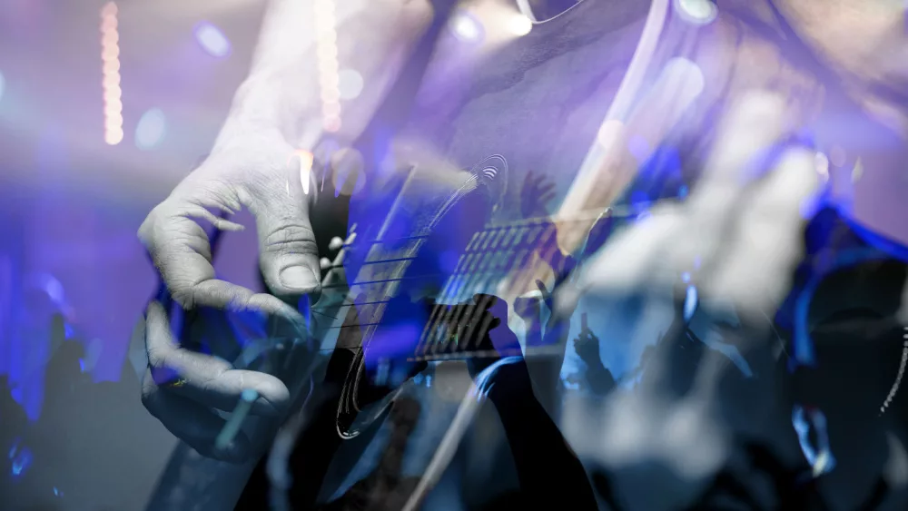 country musician on stage; close up of Guitarist with the audience.