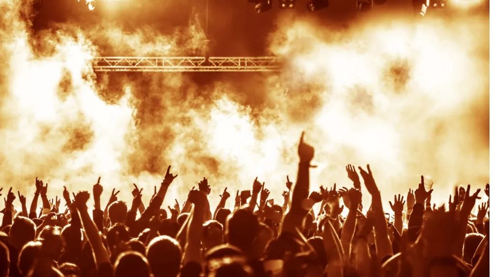 silhouettes of concert crowd in front of bright stage lights