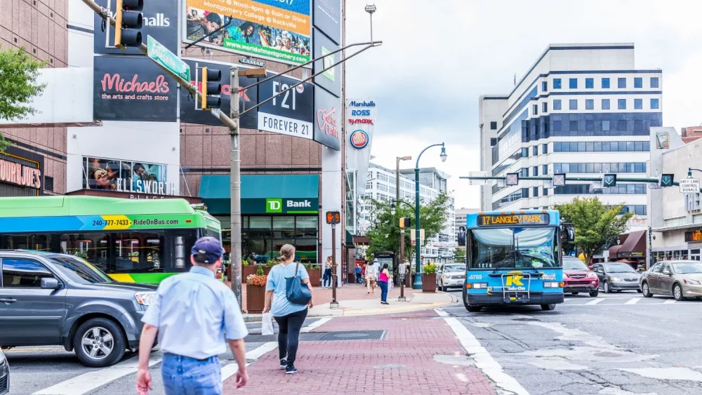 Downtown area of city in Maryland with cars on street, bus, and shopping mall stores, shops and people.