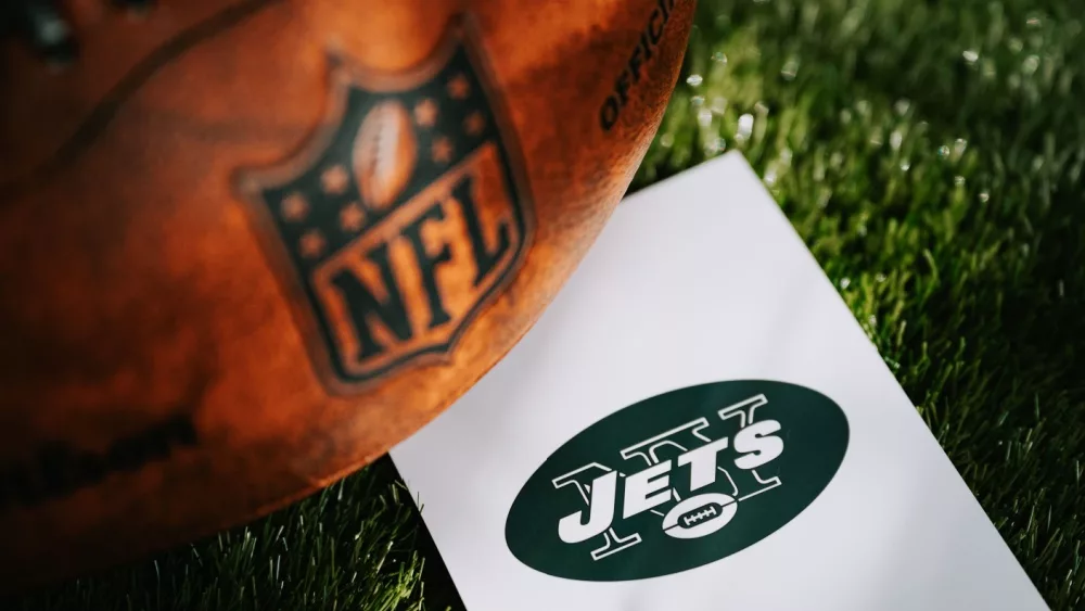 New York Jets logo on the ground and official NFL ball on green grass. Jets card, edit space