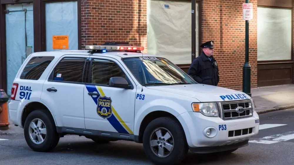 A uniformed Philadelphia Police officer stands beside a police vehicle. PHILADELPHIA, PA - JANUARY 1, 2015