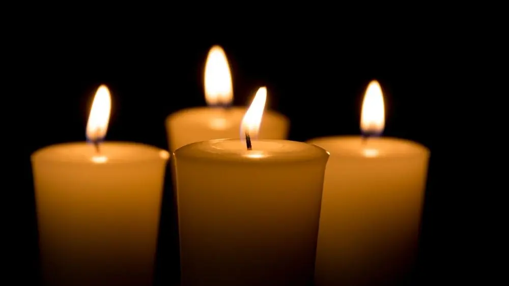 Soft focus of white candles burning, isolated on black background. Concept of religion, death, memoriam, and peace